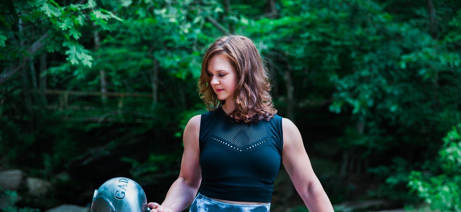 Kelly Manzone holding a steel gada by the creek